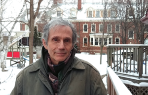 Ken Fox standing in a snowy yard with Monterey Cohousing's main building behind him